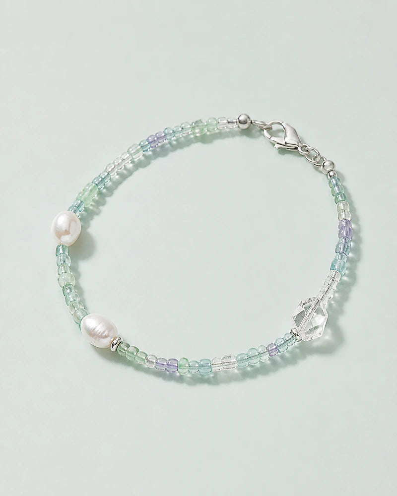 A fine bracelet of pale green and blue beads with pearl accents